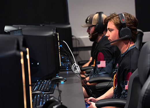 A group of students in their MSU Texas Esports jerseys play a game in the Esports lounge.
